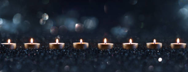 Burning candles a sign of hope Candlelights in the darkness with blurred golden bokeh. Horizontal background with short depth of field for religious rituals and spiritual meditation or grief. memorial stock pictures, royalty-free photos & images