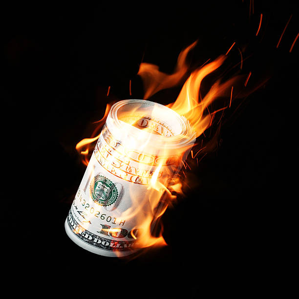 Burning one hundred dollar bills rolled stock photo
