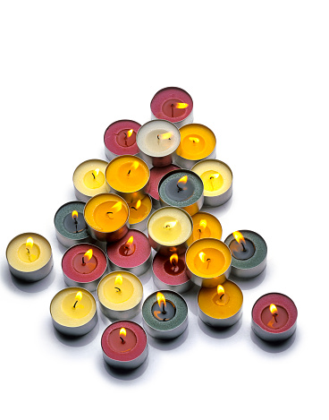 Burning paraffin candles, tealight, on a white background. High angle view.