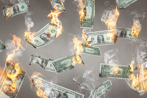 US dollar banknotes on fire are falling down. Isolated on neutral background.