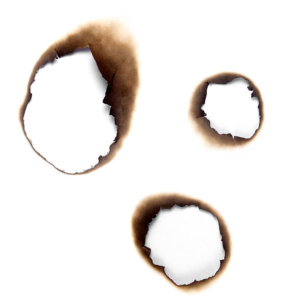 burnt holes in a piece of paper - gat stockfoto's en -beelden