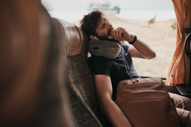 Los viajes en autobús siempre me ponen a dormir Captura recortada de un joven bostezando mientras está sentado en la almohada de viaje del autobús fotografías e imágenes de stock