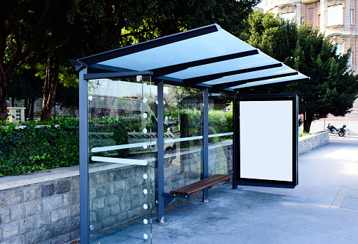 image composite of bus shelter. bus transit stop. blank white lightbox. glass structure. urban setting. city street background. asphalt sidewalk.blank poster ad commercial space. background for mockup