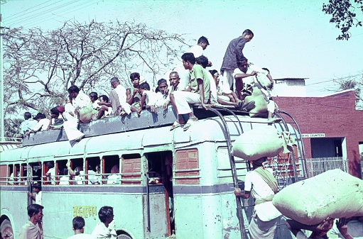 Maharashtra, India, 1972. Overcrowded bus with rooftop seats. Also: locals.