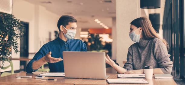 business colleagues in protective masks sitting at the office Desk close up. business colleagues in protective masks sitting at the office Desk. micro organism photos stock pictures, royalty-free photos & images