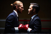 Two male business boxers looking at one another in isolation