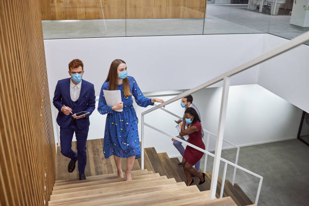 Business coworkers returning to work wearing face masks after a lockdown during coronavirus epidemic Business colleagues arriving to the office work place, wearing protective face masks during a coronavirus, covid-19 pandemic. returning stock pictures, royalty-free photos & images