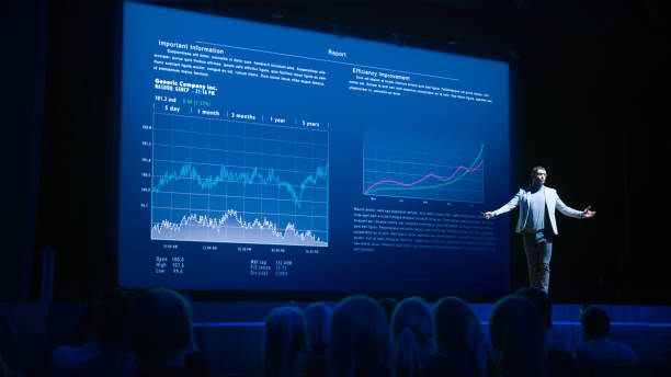 ビジネスフォーラム経済学会議ステージ:プロフェッショナルスピーカーは、スピーチで彼のレポートを締めくくり、インフォグラフィック、統計を大画面に表示します。 - プレゼン ストックフォトと画像