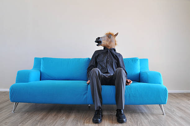 Business jackass A business person with a horse head mask sits and waits on a couch. horse mask photos stock pictures, royalty-free photos & images