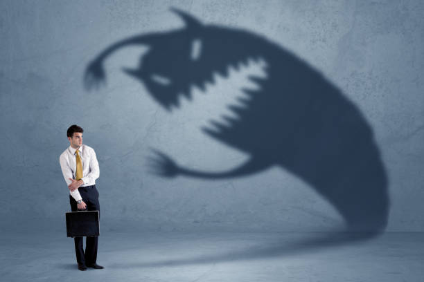Business man afraid of his own shadow monster concept stock photo