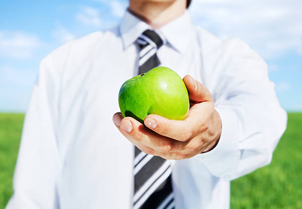 Business man holding out green apple stock photo