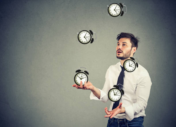 business man juggling his time alarm clocks stock photo