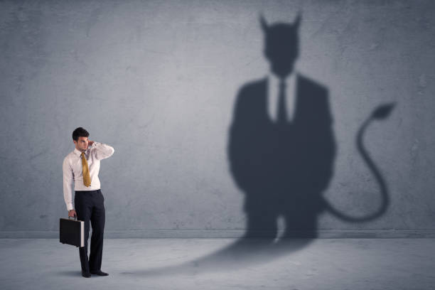 Business man looking at his own devil demon shadow concept stock photo