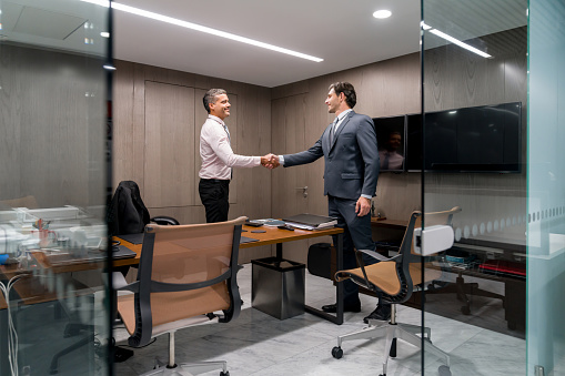 Successful business men in a meeting at the office and closing a deal with a handshake