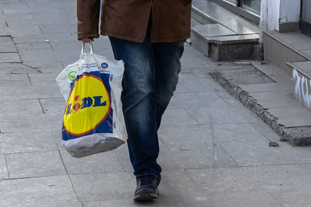 Business of foreign companies investing in Romania Bucharest, Romania - March 17, 2020: A Lidl shopping bag is carried by a passerby in downtown Bucharest. lidl stock pictures, royalty-free photos & images