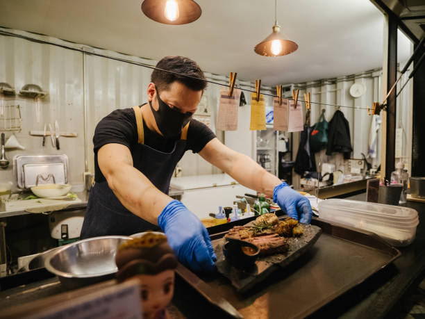 geschäftsinhaber eröffnet ein restaurant, während er eine gesichtsmaske trägt - asiatischer koch stock-fotos und bilder