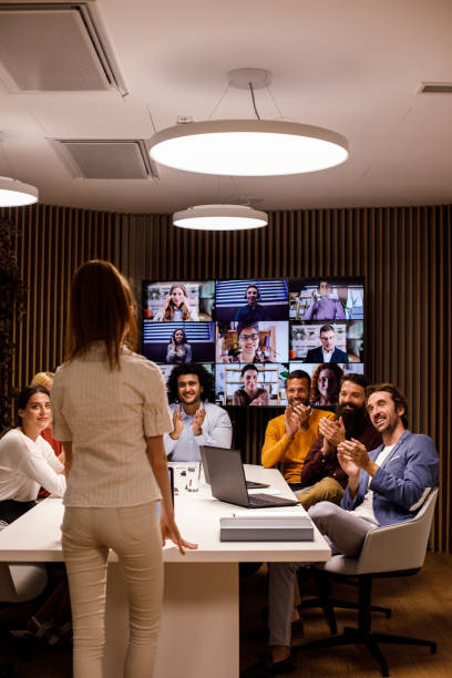 Business people applauding their female colleague on a successful presentation stock photo