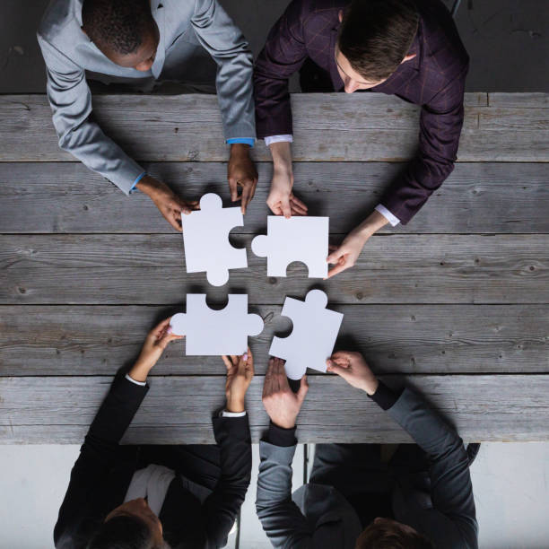 Business people assembling jigsaw puzzle stock photo