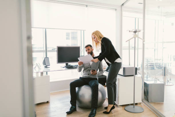Business people on meeting Business people on meeting in the office. Man sitting on fitness ball and woman holding documents yoga ball work stock pictures, royalty-free photos & images