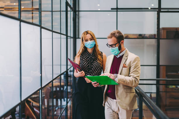 affärsmän som bär ansiktsmasker på jobbet under covid-19 pandemi - delta virus bildbanksfoton och bilder
