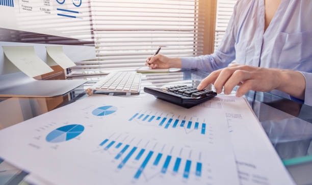 Business person working on financial report and analyzing revenue and expenses data with calculator in office Business person working on financial report and analyzing revenue and expenses data with calculator in office accounting ledger stock pictures, royalty-free photos & images