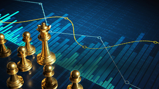 Golden chess pieces on a digital display with abstract financial charts and graphs