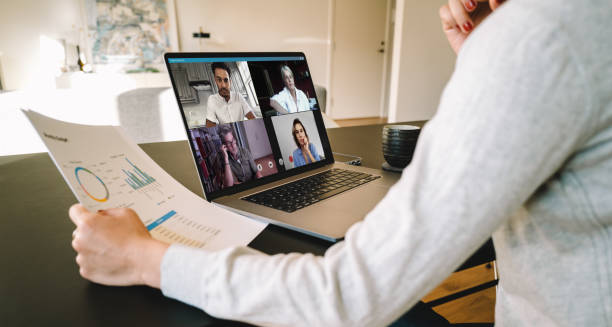 Business team in video conference Group of businessmen and businesswomen smart working from home. View from side of woman talking to her colleagues about business plan over a video conference. employee engagement stock pictures, royalty-free photos & images