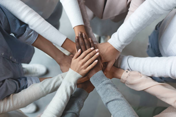 Business team putting hands together on top of each other Close up of international business team showing unity with putting their hands together on top of each other. Concept of teamwork, top view people working together stock pictures, royalty-free photos & images