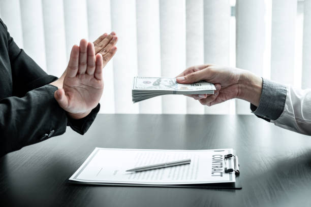Business woman refusing receive bribe money in the envelope of their partner to give success the deal contract in a corruption scam, illegal and dishonest stock photo