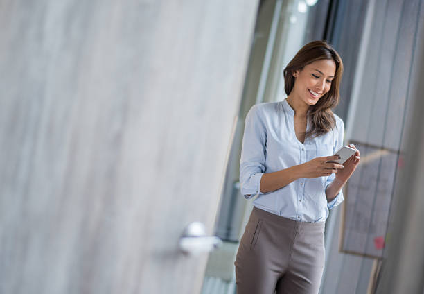 Business woman texting on her phone Successful business woman texting on her smart phone at the office asian woman using phone stock pictures, royalty-free photos & images