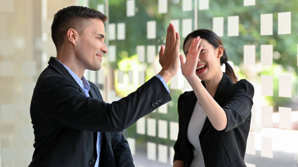 Businessman and businesswoman giving high five, celebrating, goal achievement. stock photo