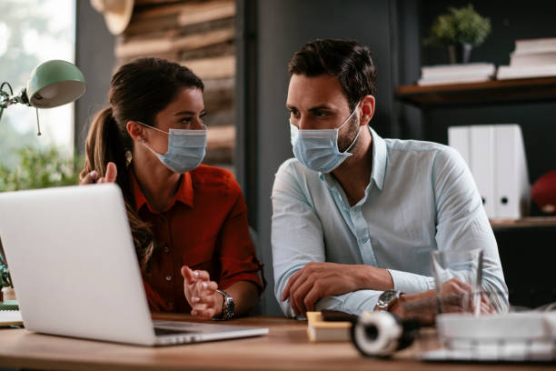 Businessman and businesswoman with medical mask in office. stock photo