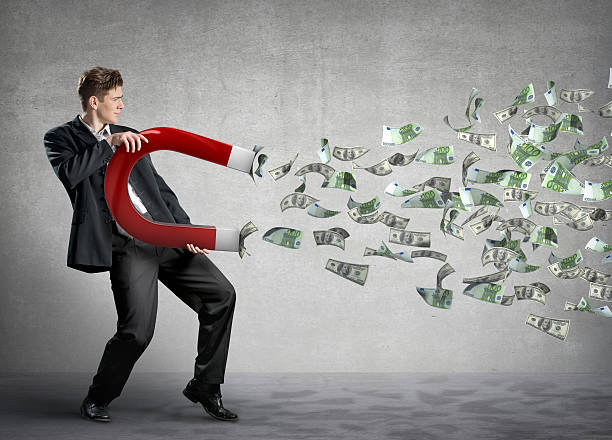 Businessman attracts lots of money with a giant magnet stock photo