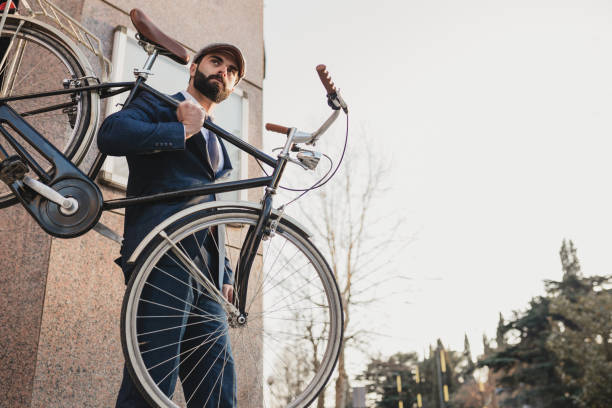Businessman caring his bicycle on the street on his shoulder stock photo