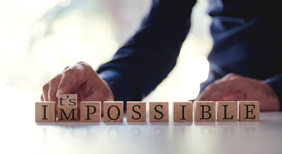 Businessman Changing The Word Impossible To Possible By Flipping Over Wooden Cube.