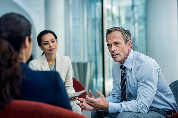 Businessman discussing strategy with colleagues Businessman discussing strategy with female colleagues in office selective focus photos stock pictures, royalty-free photos & images