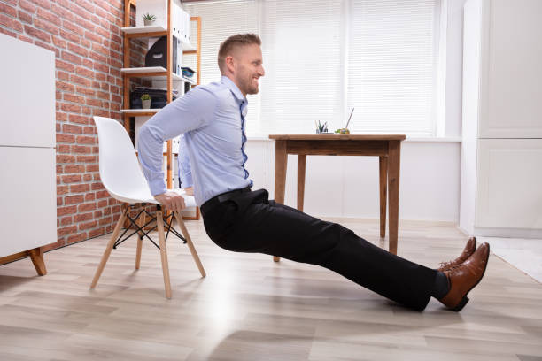 businessman doing triceps dips in office - business man shoes on desk imagens e fotografias de stock