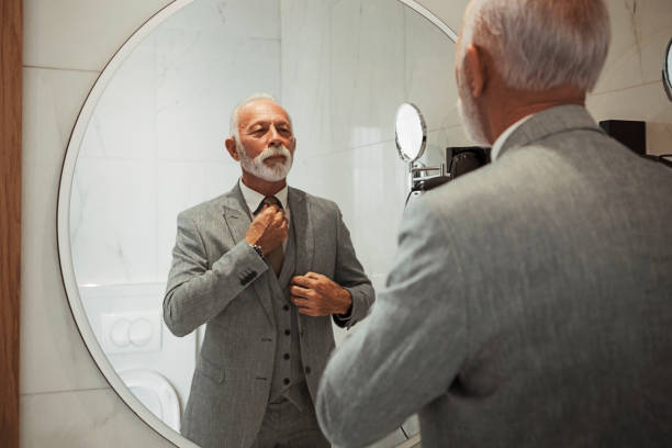 homme d'affaires s'habillant vers le haut dans la salle de bains prenant soin de la cravate - homme miroir photos et images de collection
