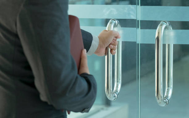 Businessman entering an office by opening out a glass door stock photo