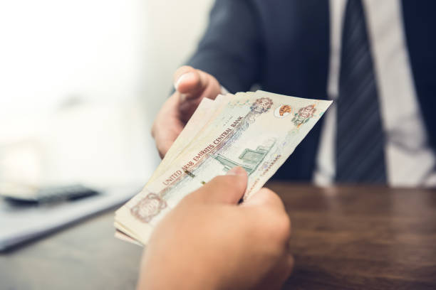 Businessman giving United Arab Emirates dirham money banknotes to his partner stock photo