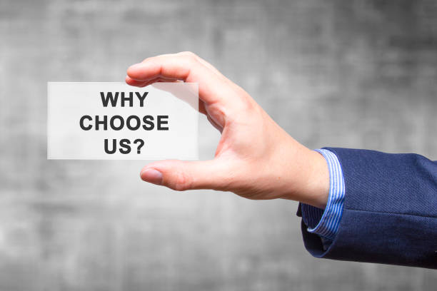 Businessman hand holding Why Choose Us? sign isolated on grey background. Business concept. Stock Photo stock photo