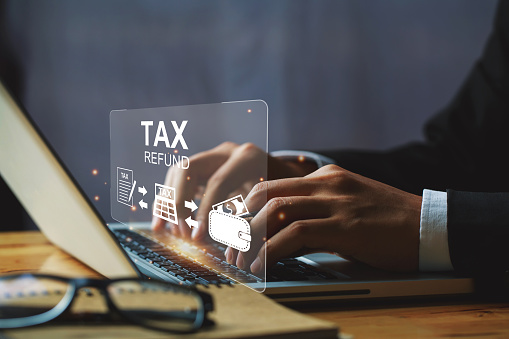 Businessman hand using a laptop with bar  TAX REFUND and refund tax of duty taxation business, tax form, and wallet money being demonstrated on the screen media, online for tax payment.tax returns