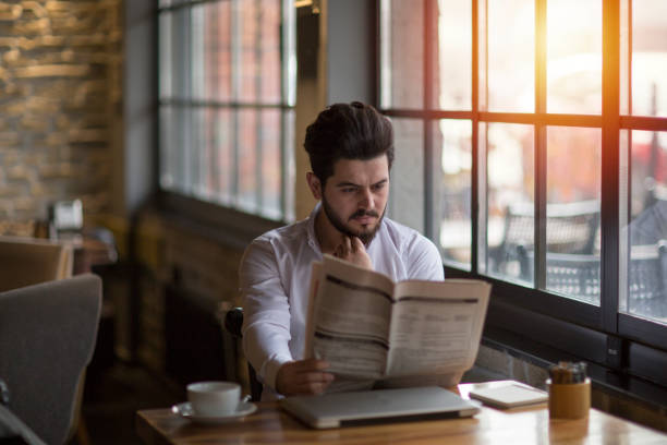 uomo d'affari che sta facendo un caffè con il giornale - young man read newspaper foto e immagini stock