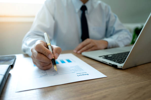 A businessman holding a pen to write documents on the desk stock photo