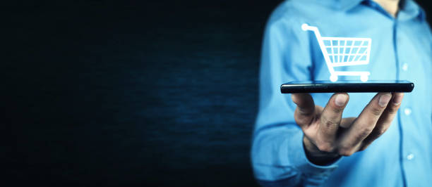 geschäftsmann hält eine telefon mit einem warenkorb-symbol. online-shopping - elektronischer handel stock-fotos und bilder