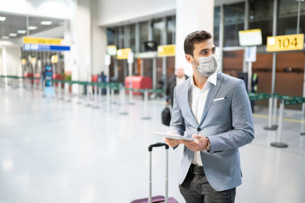 uomo d'affari in possesso di tablet digitale in aeroporto con maschera protettiva - aeroporto foto e immagini stock