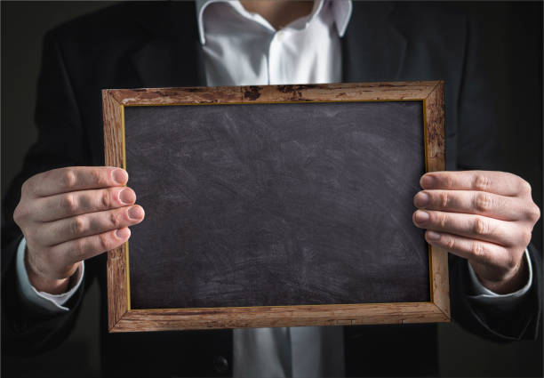 Businessman holding in hand an empty blackboard with frame stock photo