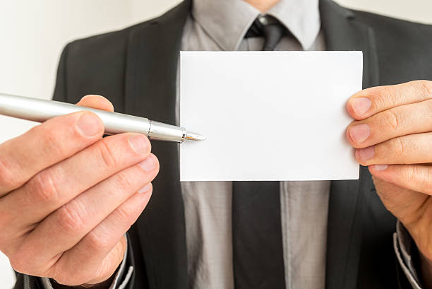 Businessman holding out a blank card and pen stock photo