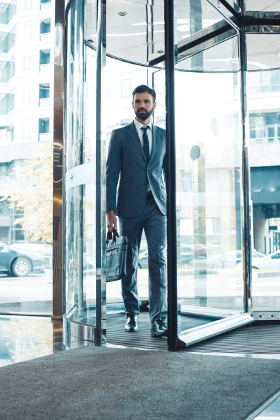 zakenman in een fromal suit in een business center betreed het gebouw met aktetas - betreden stockfoto's en -beelden