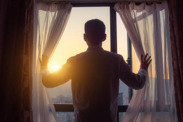 Businessman looking sunrise standing by window Businessman looking morning sunlight standing by window sunrise dawn stock pictures, royalty-free photos & images